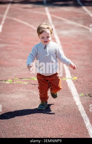 Kinder laufen auf einem sonnendurchfluteten Outdoor-Pfad, umgeben von Grün und warmem Licht Stockfoto