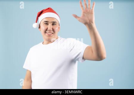 Freundlicher junger Mann, der mit der Hand winkt und der Kamera Hallo sagt Stockfoto