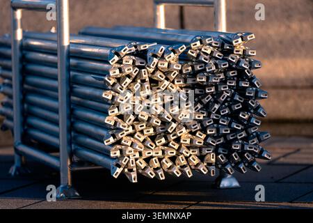 Warmes Sonnenuntergangslicht reflektiert auf gestapelten Metallgerüsten, die ordentlich auf dem Bürgersteig angeordnet sind Stockfoto
