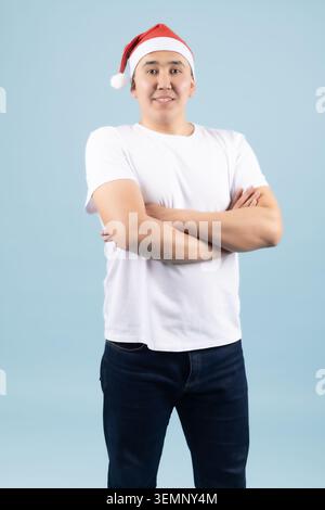 Selbstbewusster junger Mann mit rotem weihnachtsmann, der mit überkreuzten Armen steht Stockfoto