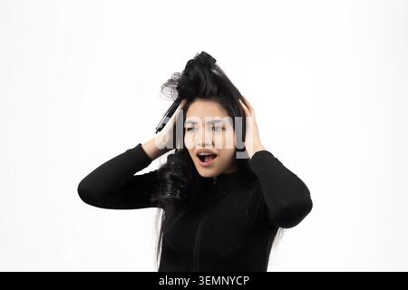 Eine gestresste junge Frau, die ihre unordentlichen Haare zieht und Kopfschmerzen hat Stockfoto