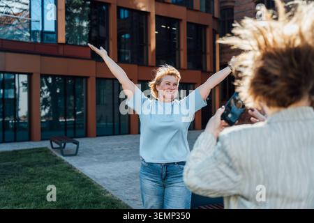 Seniorin posiert für Smartphone Photo im modernen Stadthof Stockfoto