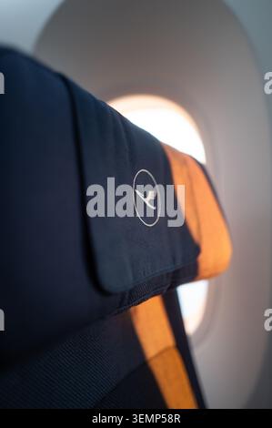 Lufthansa Allegris Economy Class-Kopfstütze beleuchtet durch warmes Sonnenlicht in einer Boeing 787 Dreamliner während eines Inlandsflugs in Deutschland. Stockfoto