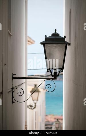 Laternenpfahl in einer engen Gasse in der Altstadt von Altea, Alicante, Valencianische Gemeinschaft, Spanien, mit dem Meer im Hintergrund Stockfoto