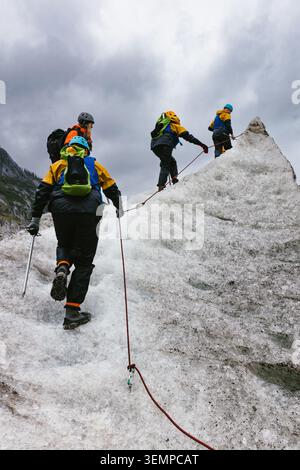Menschen klettern auf einem Eisberg mit Stacheln und Seilen auf dem Gletscher Stockfoto