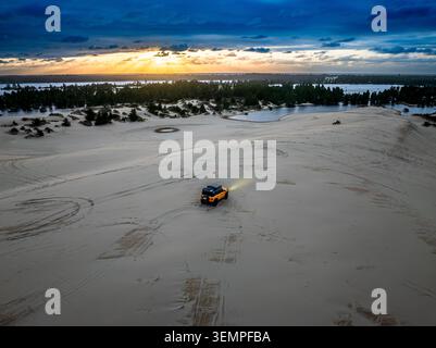Orangefarbenes Geländefahrzeug fährt über weite Sanddünen Stockfoto