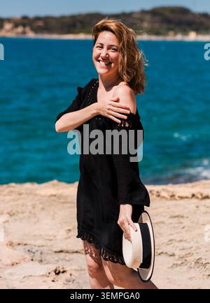 Glückliche Frau, die einen sonnigen Tag am Strand genießt Stockfoto