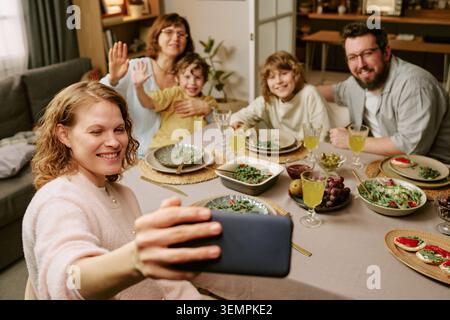Die Familie macht ein Smartphone-Selfie während des Sonntagessens zu Hause Stockfoto