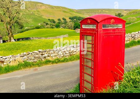 Das ländliche Dorf Keld in Swaledale, Yorkshire Dales, Großbritannien, mit gelben Wildblumenwiesen und legendären, altmodischen roten Telefonzellen und Stockfoto