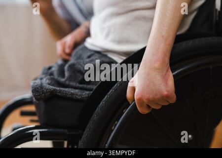 Nahaufnahme der Hand eines amputierten Behinderten am Rollstuhlrad Stockfoto