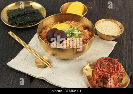 Koreanische scharfe Remayeon mit Kimchi, Nori Sheet und Danmuji Beilage. Instant Food on Gold Bowl Stockfoto