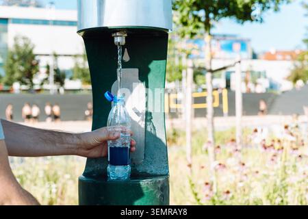 Handauffüllung der Plastikwasserflasche am öffentlichen Trinkbrunnen, Nahaufnahme Stockfoto