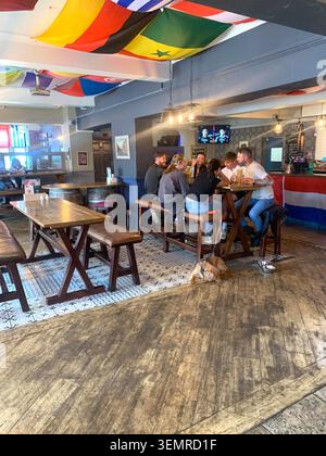 Freunde versammeln sich an einem Tisch in einem lebhaften Pub, der mit internationalen Flaggen dekoriert ist, in einem warmen Trompetenlokal Weston Favell Northampton England Stockfoto