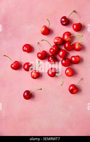Frische süße Kirschen auf rosafarbenem Hintergrund, Draufsicht. Sommerobst-Komposition mit Kopierraum. Stockfoto