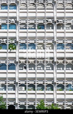 Moderne Wohnhausfassade mit sich wiederholenden geometrischen Balkonen, Fenstern und Pflanzen in Madrid, Spanien. Stockfoto