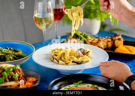 Köstliches Pasta-Gericht, serviert mit lebhaften Getränken und bunten Tellern Stockfoto