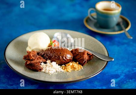 Köstliche Schokoladenmousse mit cremigem Eis und Espresso auf einem lebhaften blauen Tisch Stockfoto