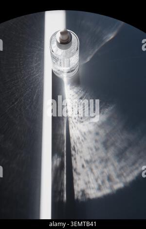 Serumflasche aus Glas erzeugt Lichtmuster und ätzende Reflexionen auf runder Oberfläche Stockfoto