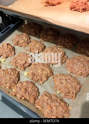 Rinderleber, Zucchini und Karotten-Fleischbällchen sitzen auf einem mit Pergamentpapier ausgelegten Blech in einer Küche. Die Fleischbällchen sind geformt und können im Ofen gekocht werden. Stockfoto