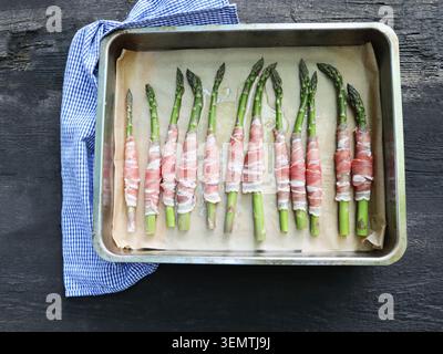 Mit Schinken umwickelte Spargel-Speere auf einem Backblech Stockfoto