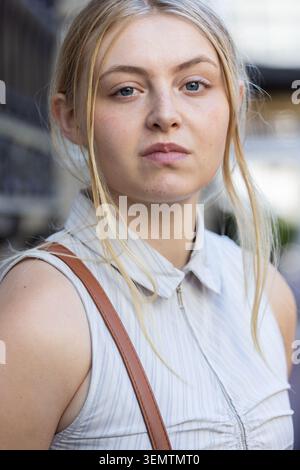 Kamera für eine Frau im Stehen auf dem städtischen Gehweg mit ärmellosem Oberteil und braunem Lederriemen Stockfoto