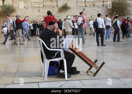Orthodoxer jüdischer Mann liest Gebetsbuch auf dem Western Wall plaza mit Menschenmenge, Jerusalem, Israel Stockfoto
