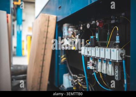 Nahaufnahme komplexer Industrieanlagen mit Pneumatikventilen, Verkabelung und Steuersystemen innerhalb einer Produktionsanlage Stockfoto