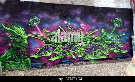 Stockholm, Schweden, 17. Mai 2026. Lebendiges Graffiti-Fototapete mit neongrüner außerirdischer Kreatur, stilisierten Schriften und UFOs, die über ein verwittertes Tier gesprüht sind Stockfoto