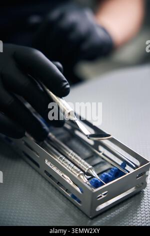 Erwachsener Mann mit Handschuhen, der Zahnwerkzeuge in der Praxis aufnimmt Stockfoto