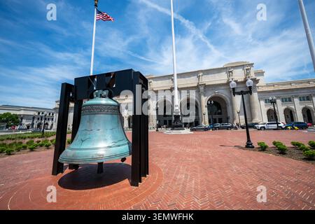 American Legion Freedom Bell Columbus Plaza Union Station Washington DC / WASHINGTON D.C., Vereinigte Staaten — die American Legion Freedom Bell befindet sich auf ihrem runden Backsteinsockel am Columbus Plaza, dem halbkreisförmigen Vorplatz Daniel Burnham, der als zeremonielles Tor zur Union Station entworfen wurde, die 1907 eröffnet wurde. Drei Fahnenmasten mit vergoldeten Adlern flankieren die Glocke und spiegeln bewusst die drei Fahnenmasten vor dem Markusdom in Venedig wider. Nachdem er vom 1. April 1975 bis zum 31. Dezember 1976 alle 48 angrenzenden bundesstaaten mit dem American Freedom Train bereist hatte, der schätzungsweise 7 Millionen Visi erreichte Stockfoto