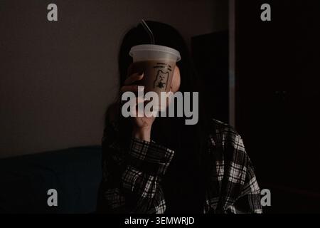 Frau hält Kaffeetasse in Dunkelkammer Stockfoto