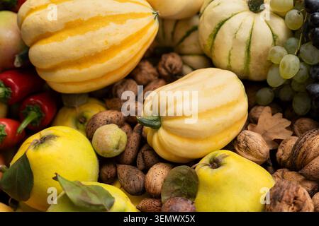 Rustikaler Herbstlese-Korb mit Zierkürzeln, frischen Trauben, Birnen, Äpfeln und Walnüssen im Freien auf herabfallenden Blättern. Lateinisches Ornamental Gou Stockfoto