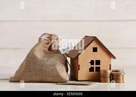Papier mit WORTMIETE, Hausfigur, Münzen und Tasche auf weißem Holztisch Stockfoto