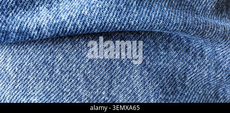 Hintergrund aus blauem Denim-Stoff mit diagonalem Webmuster und dezenten Falten, Makroansicht aus nächster Nähe Stockfoto