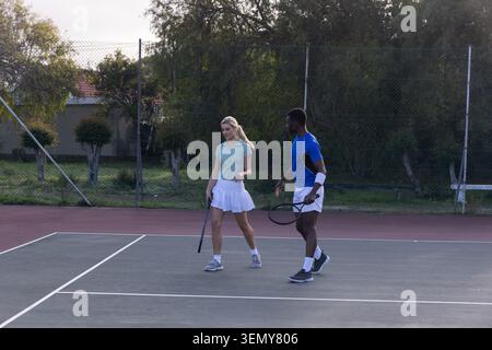 Verschiedene Tennisteams laufen auf dem Hartplatz, halten Schläger, tragen Sportbekleidung und Turnschuhe Stockfoto