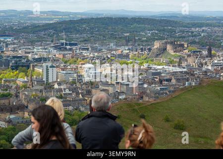 Menschen, die vom Gipfel des Arthurs Seat, Holyrood Park, Edinburgh, ein Panorama von Edinburgh City und Edinburgh Castle genießen. Stockfoto