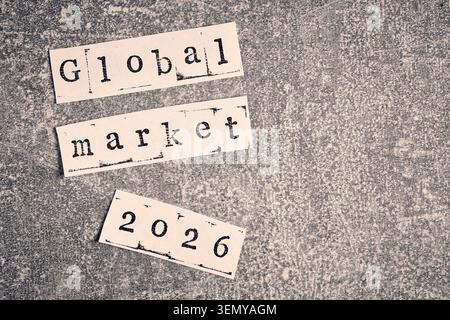 Global Market 2026 Phrase machte Papierstücke auf dunkler, gesprenkelter Steinstruktur im Retro-Stil Stockfoto