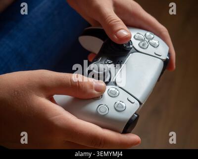 Sitges, Spanien - 06. Juni 2026: Eine redaktionelle Nahaufnahme einer Person, die Hände hält und mit einer klassischen PlayStation 5 du in weiß und Schwarz spielt Stockfoto