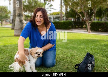 Frau mit Shih Tzu Hund im Park. Freizeit mit einem Haustier im Freien. Stockfoto