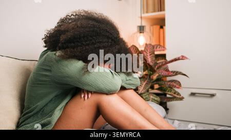 Junge Frau, Die Auf Dem Bett Sitzt Und Sich Die Knie Im Schlafzimmer Umarmte Und Sich Traurig Und Ängstlich Fühlte Stockfoto
