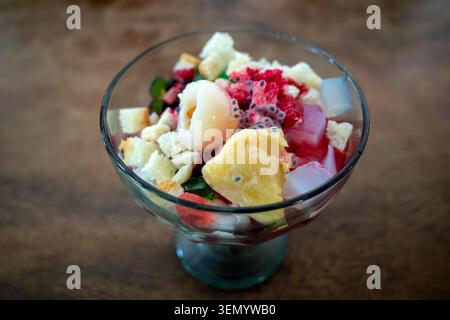 Eine frische tropische Schüssel mit fruchtigem Eis, Kiwi, Melone, Erdbeerfrüchten auf einem alten Holztisch. Stockfoto