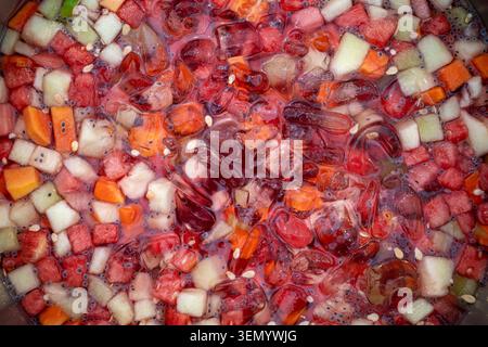 Nahaufnahme eines erfrischenden Getränks mit einer Mischung aus klaren Eiswürfeln und frischen Fruchtscheiben, die lebendige Fruchtfarben betonen. Stockfoto