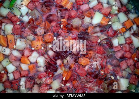 Nahaufnahme eines erfrischenden Getränks mit einer Mischung aus klaren Eiswürfeln und frischen Fruchtscheiben, die lebendige Fruchtfarben betonen. Stockfoto