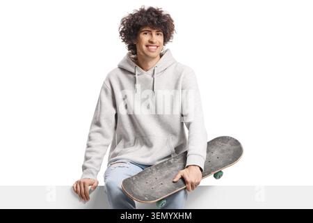 Ein Typ mit einem Longboard, der auf einer weißen Platte sitzt, isoliert auf weißem Hintergrund Stockfoto