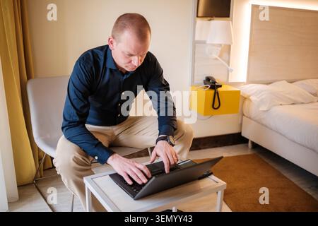 Mann tippt auf einem Laptop, beschäftigt mit der Arbeit, während er geschäftlich unterwegs ist Stockfoto