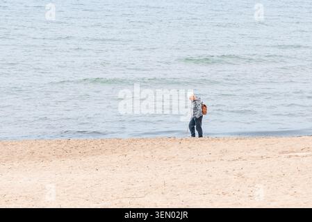 Enttäuschter älterer Mann, der eine ältere Frau herunterschaute, die allein an einem geschäftigen Sommerstrand mit einem Wanderstock stand. Klaipeda, Litauen 06-06-2026. Stockfoto