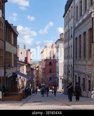 Blick aus einem hohen Winkel auf eine steile historische Kopfsteinpflasterstraße mit Fußgängern in Lyon, Frankreich. Stockfoto