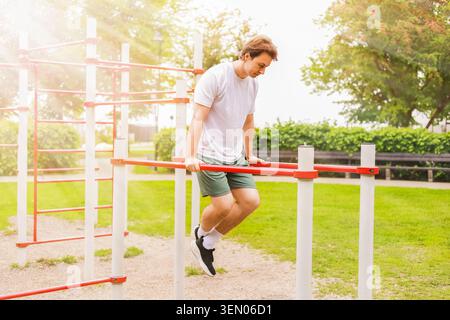 Mann, der auf einem Sportplatz im Freien Dips an parallelen Bars durchführt. Calisthenics Fitness-Training im Park an einem sonnigen Tag. Hochwertige Fotos Stockfoto