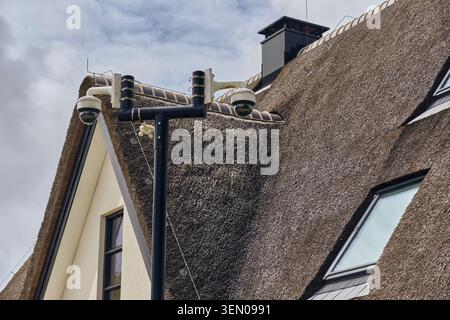 Überwachungskameras für den Heimschutz auf einem Strohdach in Stroe, niederlande, moderne Technologie mit traditioneller Architektur Stockfoto
