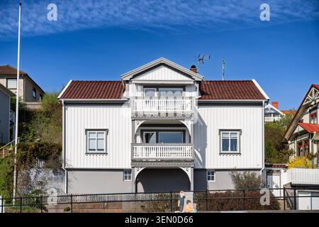Weißes Holzhaus mit Balkon und rotem Dach in sonniger Küstenlage Stockfoto